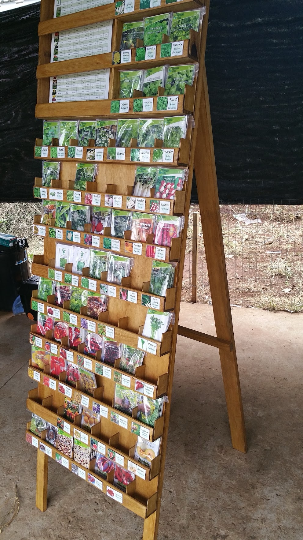 The Green Guy organic seed packets arranged on a wooden display stand