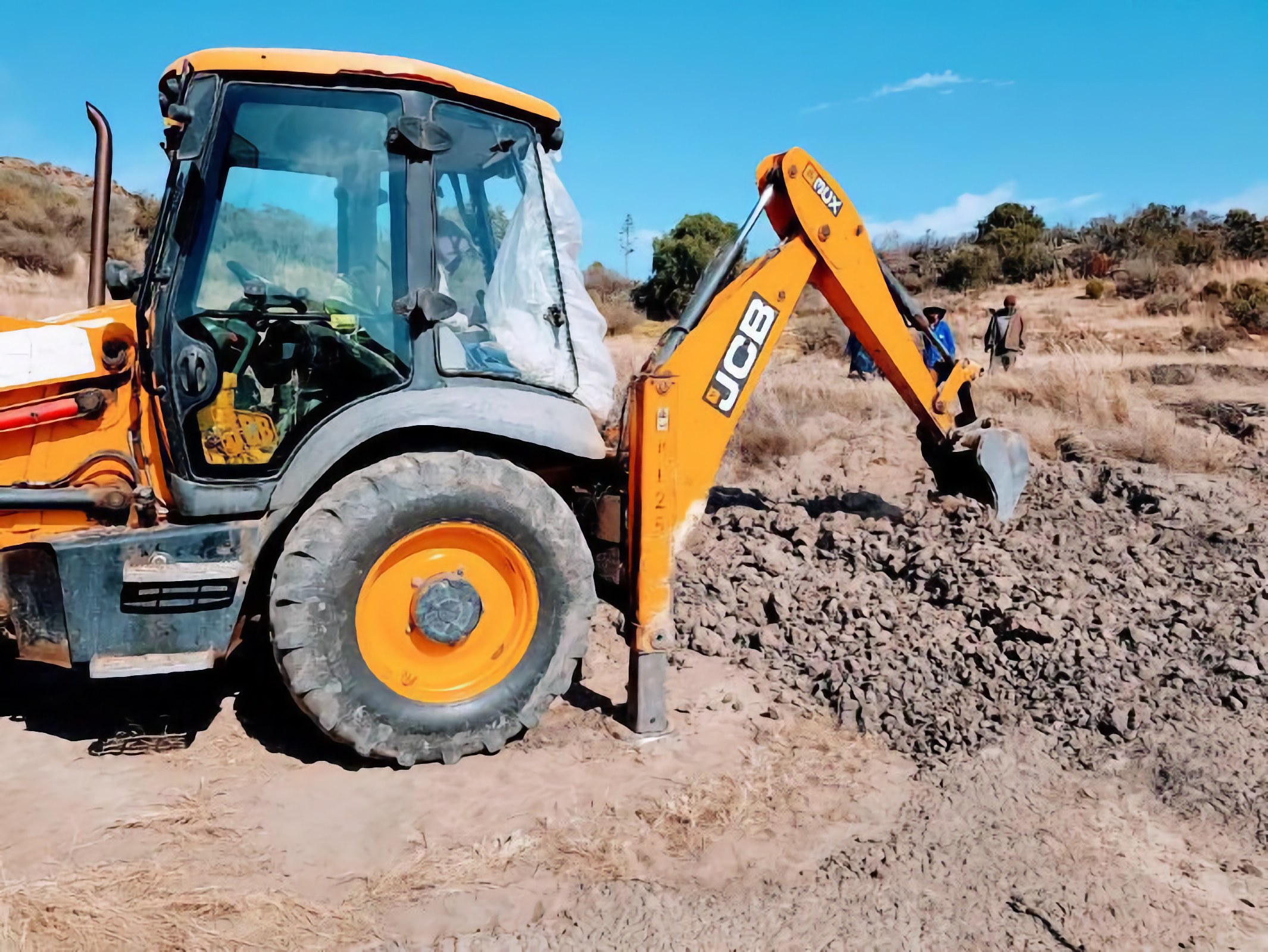 A backhoe carrying out earthworks on a Lesotho permaculture garden site