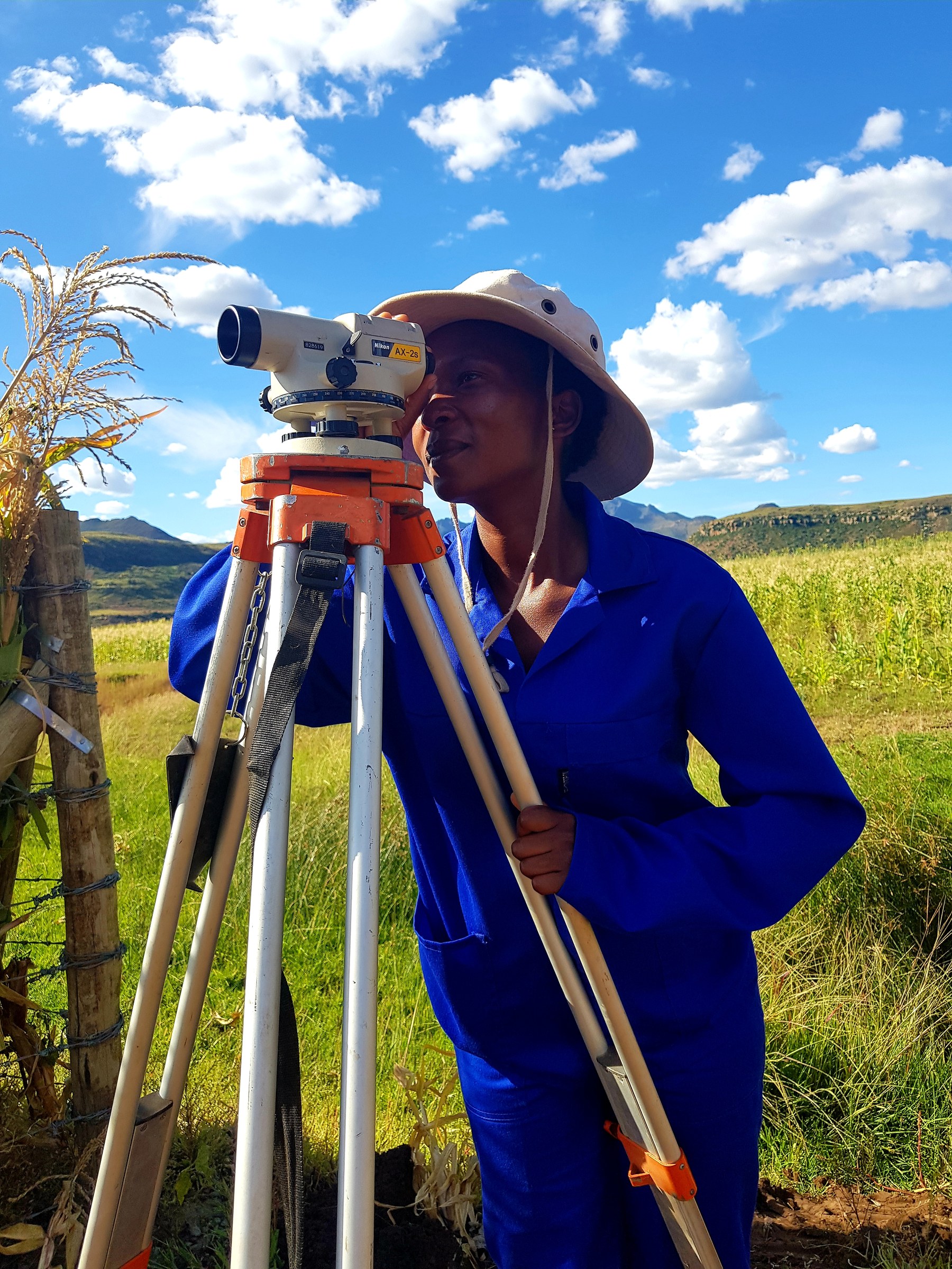 A field team member surveying a Lesotho site with a dumpy level