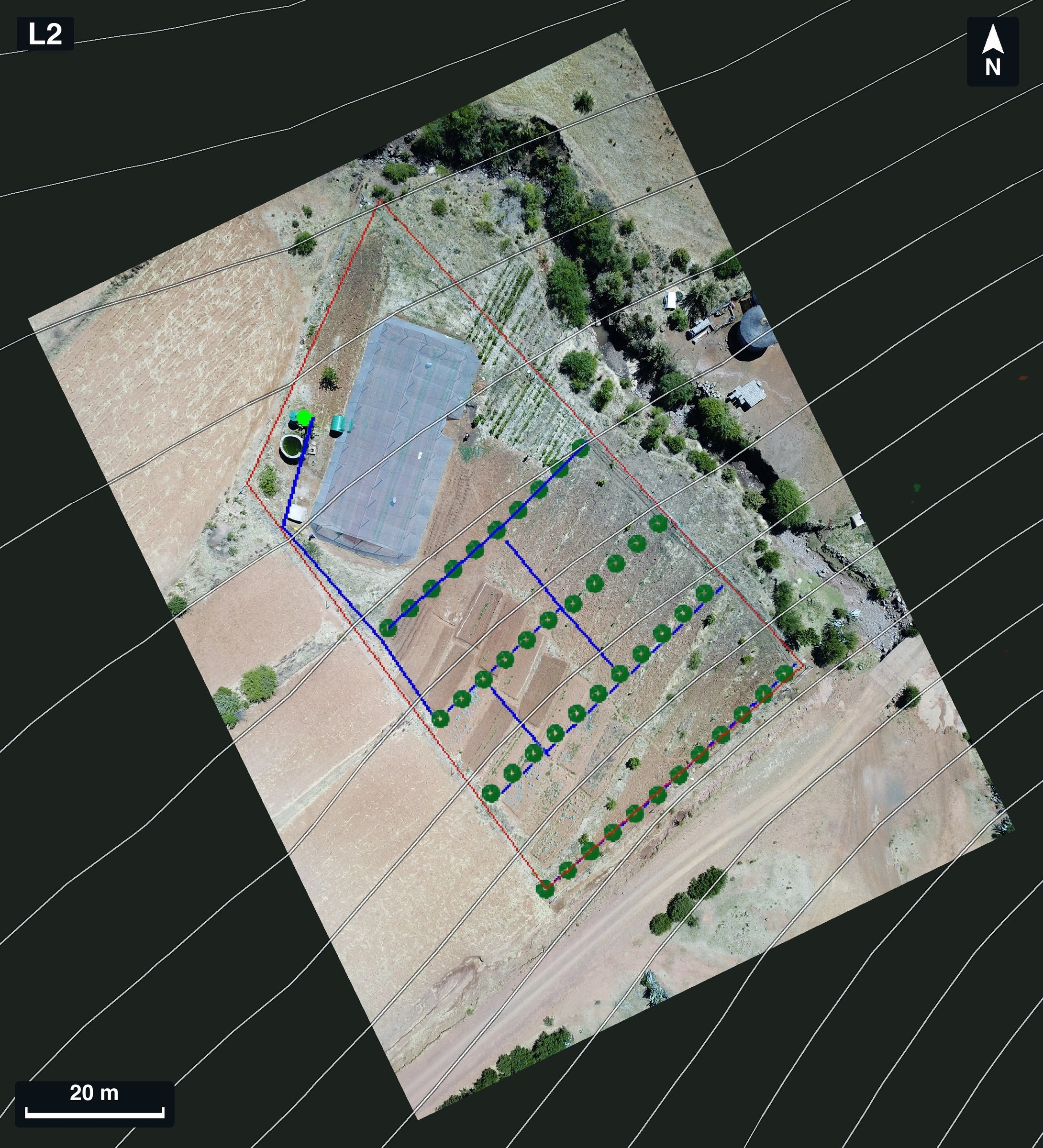 Drone orthophoto of garden L2 with rows of green tree markers, blue drip lines, a red boundary and a tank symbol drawn over it, a large roofed structure in the middle and contour lines across the frame