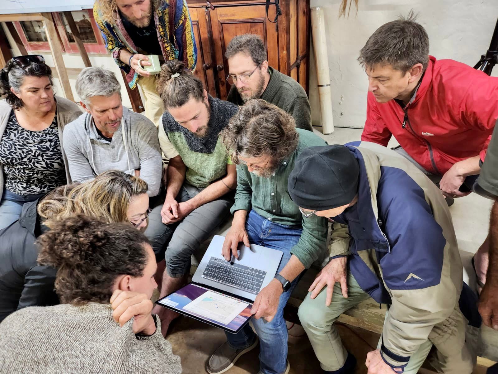 Participants gathered around a laptop during a professional-development workshop with Geoff Lawton