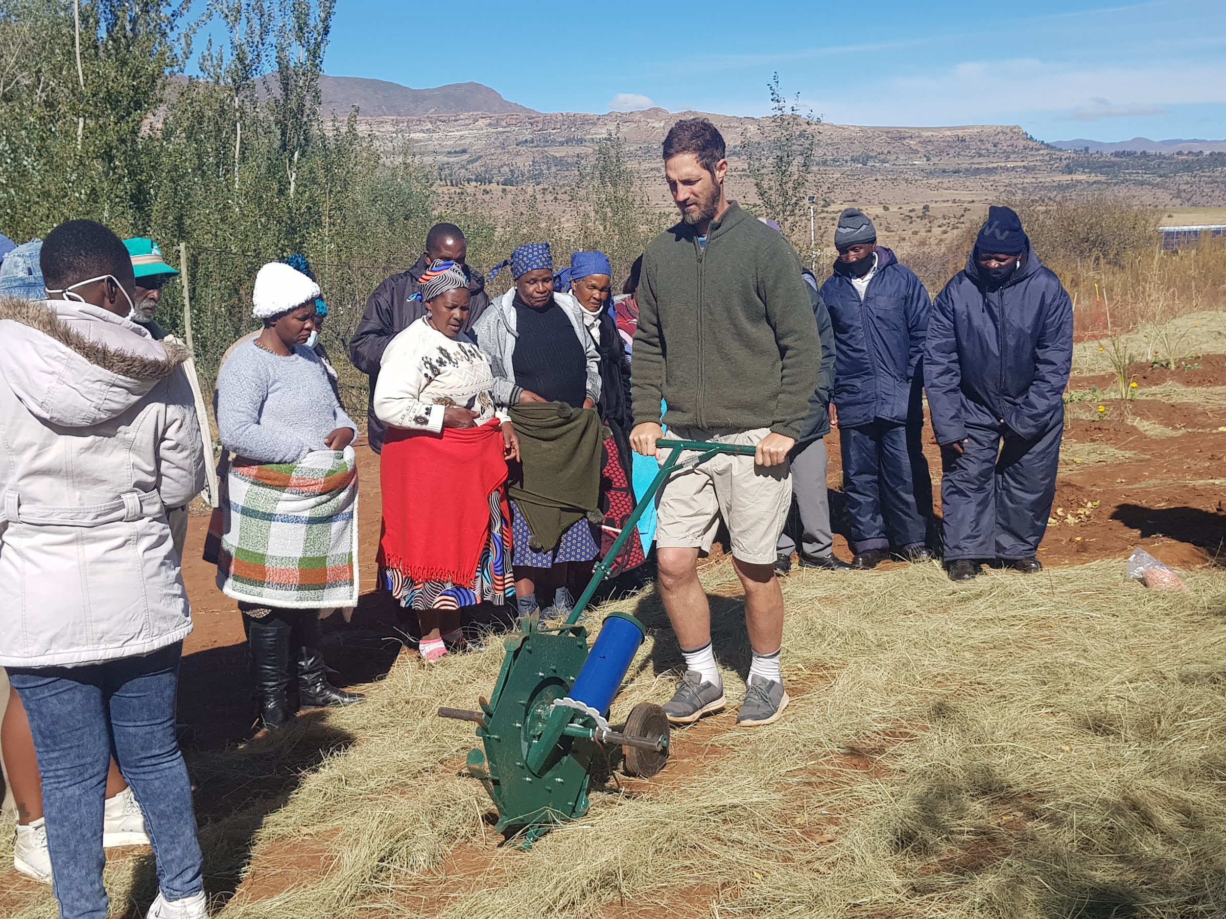 Rory Clark demonstrating a manual minimum-tillage implement to a group of participants in a mulched Lesotho field