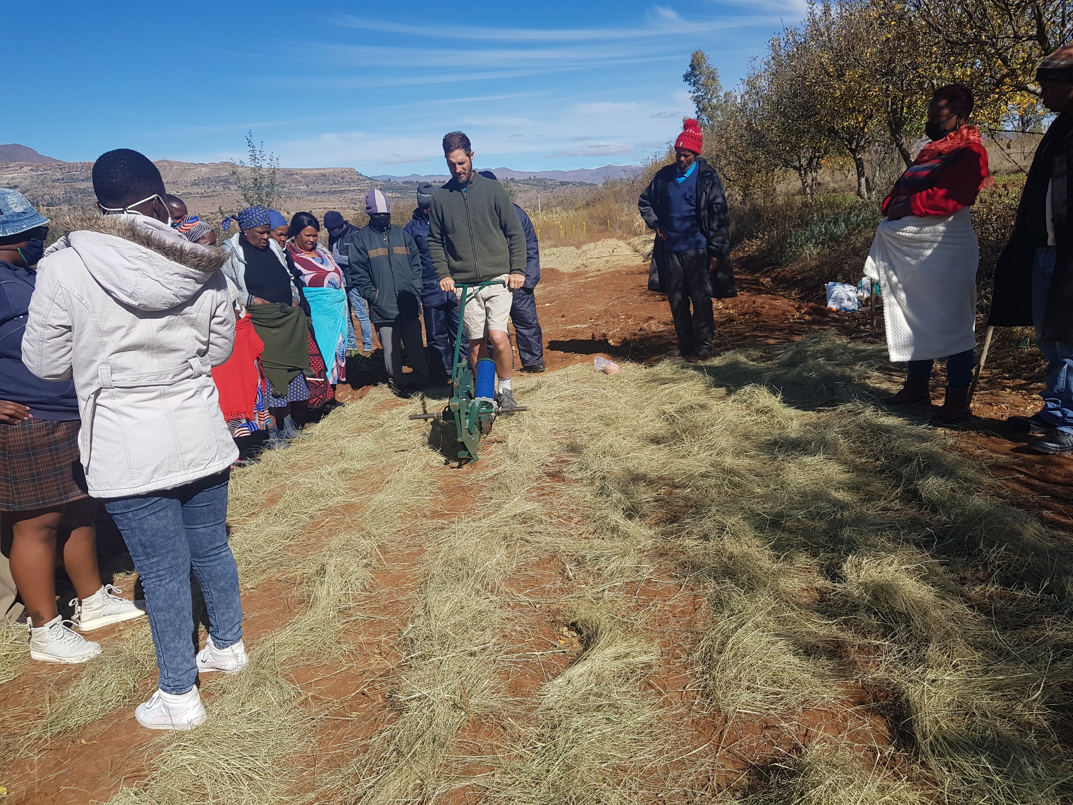 Rory Clark demonstrating a no-till planter with participants gathered around a mulched bed in Lesotho