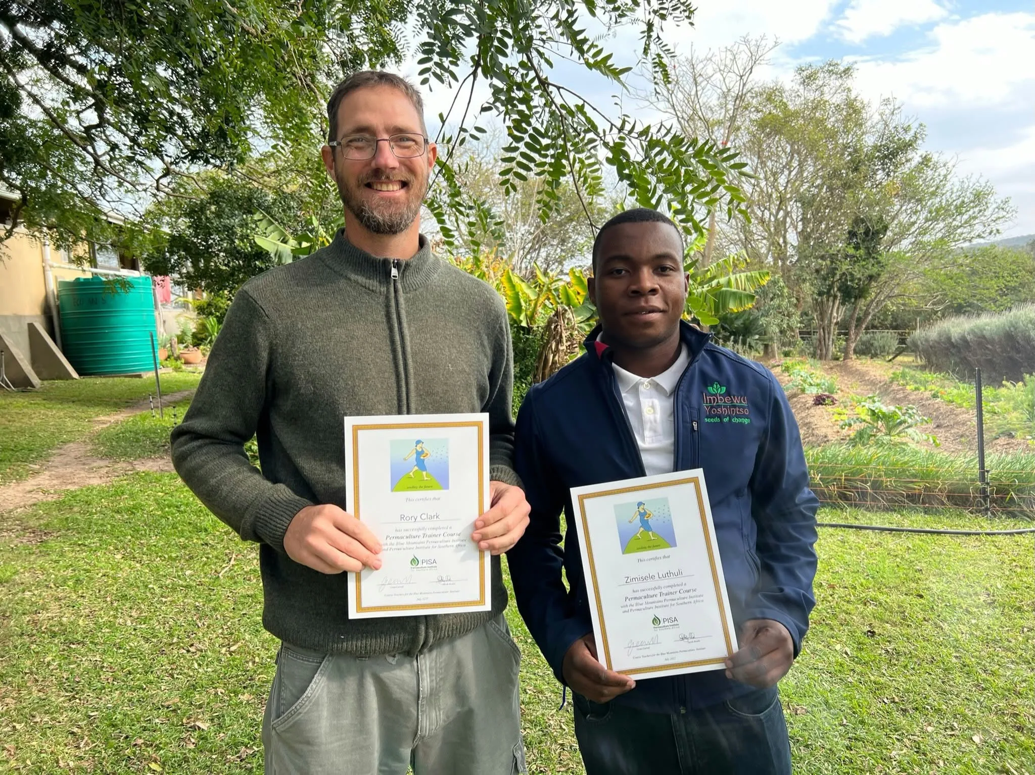Rory Clark and Zimisele Luthuli holding permaculture trainer-course certificates