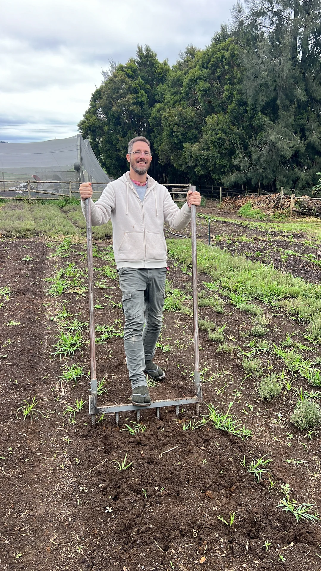 Rory Clark in a white hoodie standing on a broadfork in a permanent growing bed at Tatsfield